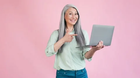 Middle aged lady point netbook suggest buy isolated pastel color background Stock Footage 165348474