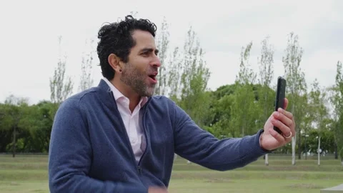 Middle-aged Latin man sitting on a bench in a rural area greeting a loved o.. Stock Footage 237890223
