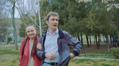 A middle-aged loving couple approaches a tree in the park and talks,the man Stock Footage 129503965