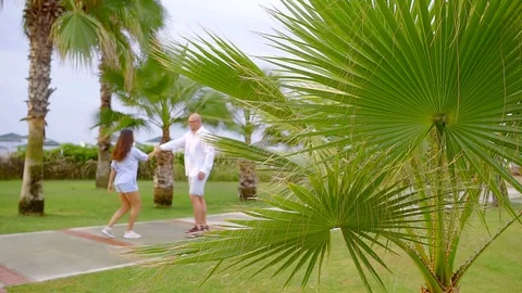 Middle aged loving pair is dancing in a garden in summer day, woman is whirling 库存影片 96998267