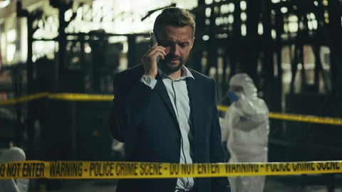 Middle-aged male detective talking on phone while examining evidence bag Stock Footage 337641091