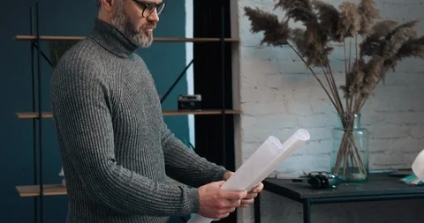 Middle aged male Engineer standing in the Office room, taking his Drawings on Stock Footage 126244144