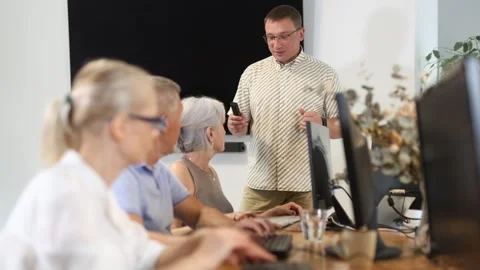 Middle-aged male instructor teaching computer skills to old students during IT Stock Footage 311838108