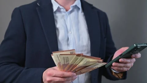A middle-aged male with light skin is holding a large stack euro of cash in one Stock Footage 338300052