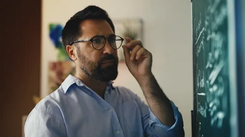 Middle-aged male scientist solving theory on chalkboard, focused on math problem Stock Footage 311461642