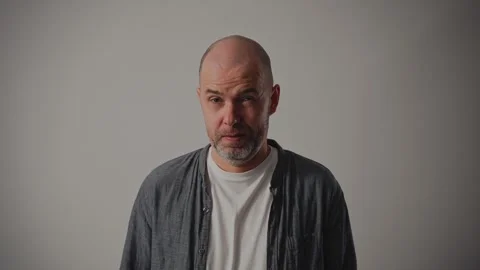 A middle-aged man against a white background. His facial expression conveys an Stock-Footage 295360067