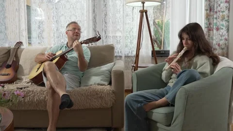 A middle-aged man and a 12-year-old girl playing guitar and a recorder Stock Footage 318784105