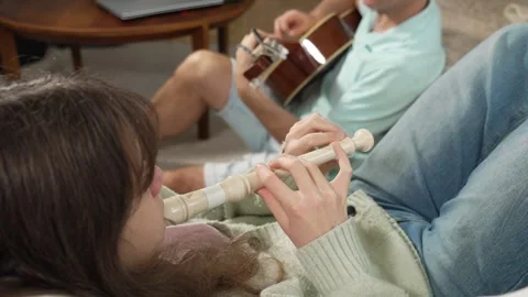 A middle-aged man and a 12-year-old girl playing guitar and a recorder Stock Footage 318784902