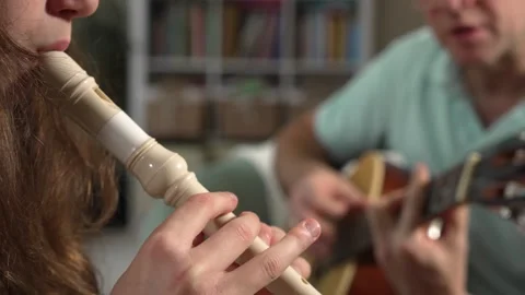 A middle-aged man and a 12-year-old girl playing guitar and a recorder Stock Footage 318785641