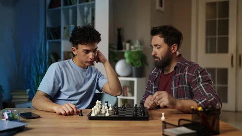 Middle-aged man and his teen son playing chess at home, spending time together Stock Footage 329841061
