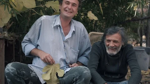 Middle-aged man and white-haired old man sitting outdoors and laughing 4K Stock Footage 85672098