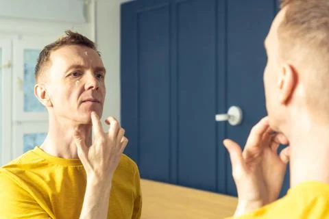 Middle aged man apply moisturizing cream on clear facial areas. Male portrait in Stock Photos