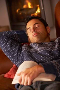 Middle Aged Man Asleep With Book By Cosy Log Fire Stock Photos