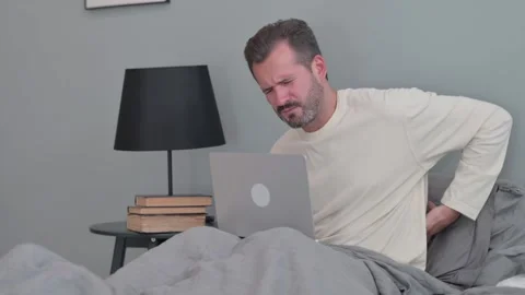 Middle Aged Man with Back Pain Working on Laptop in Bed Stock Footage 287899009