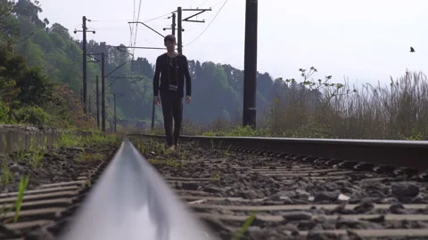 Middle aged man with backpack walks along the rails of an old railway along Stock Footage 262230182
