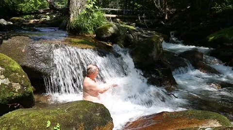 Middle-aged man bathes in a waterfall Stock Footage 67253100