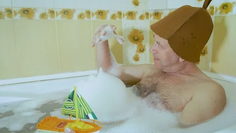Middle-aged man in the bathroom playing with a baby boat Video stock 108617306