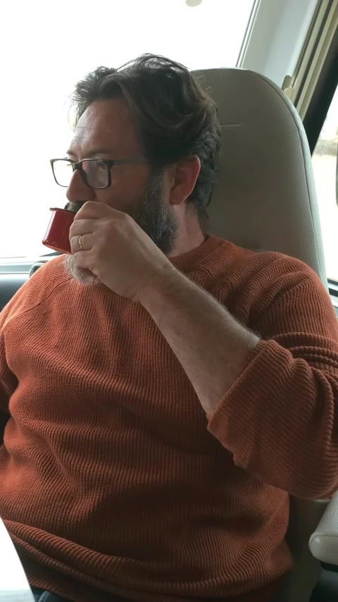 Middle-aged man with a beard and glasses sitting comfortably in a camper van Stock Footage 344398058