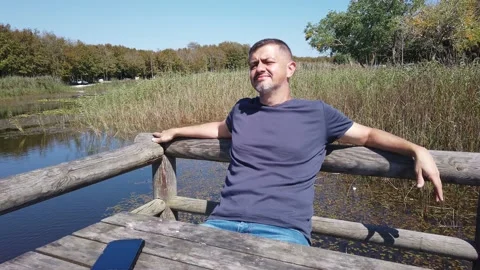 Middle-aged man with beard in casual clothes is resting in nature Stock Footage 139446311