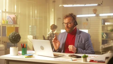 A middle aged man with a beard communicates via video conference using a laptop Stock Footage 238506514