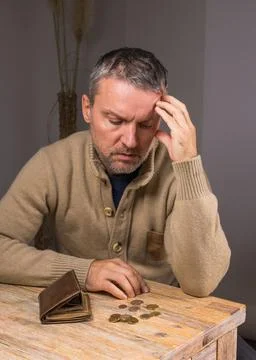 Middle aged man with beard counts coins.  Financial difficulties. Stock Photos