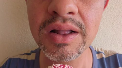 Middle-aged man with beard eats donut with pink sugar glaze. Portrait. Close-up Stock Footage 133601425