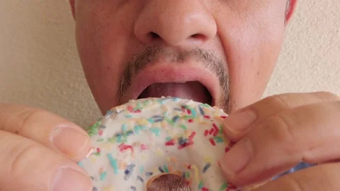 Middle-aged man with beard eats donut with pink sugar glaze. Portrait. Close-up Stock Footage 133601426