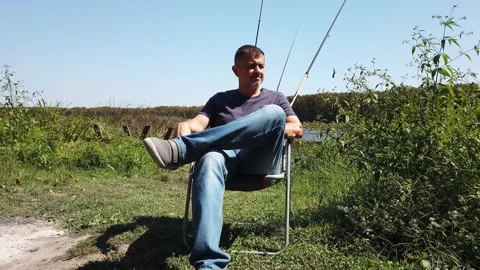 Middle-aged man with beard. guy sits in tourist chair, smokes, rests. Vidéo 143893446