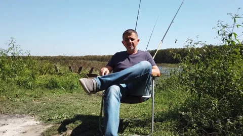 Middle-aged man with beard. guy sits in tourist chair, smokes, rests. Stock Footage 143893447