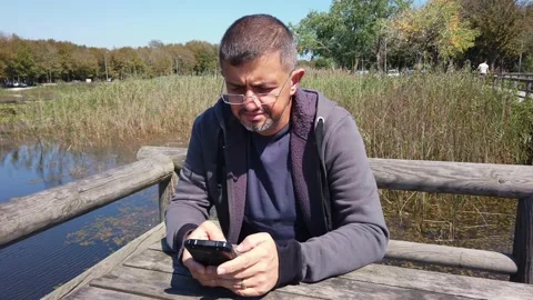 Middle-aged man with beard looks at smartphone screen. Gadget addictions concept Stock Footage 139444434