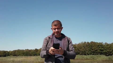Middle-aged man with beard looks at smartphone screen. Gadget addictions concept Stock Footage 139444440