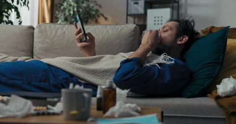 Middle-aged man with beard is lying on sofa and covered with blanket. Man with 库存影片 218324184