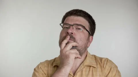 A middle-aged man with a beard talks thoughtfully on a gray background. Stock Footage 156083333