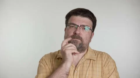 A middle-aged man with a beard talks thoughtfully on a gray background. Stock-Footage 156083336
