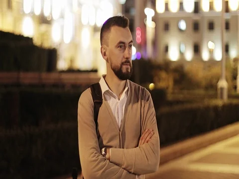 Middle aged man with a beard is waiting for someone on the background of a night Stock Footage 79802235