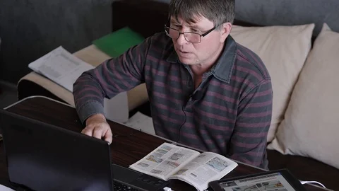A middle-aged man behind a laptop is an online broadcast Stock Footage 129894210