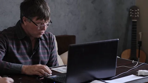 A middle-aged man behind a laptop is an online broadcast Stock Footage 129894255