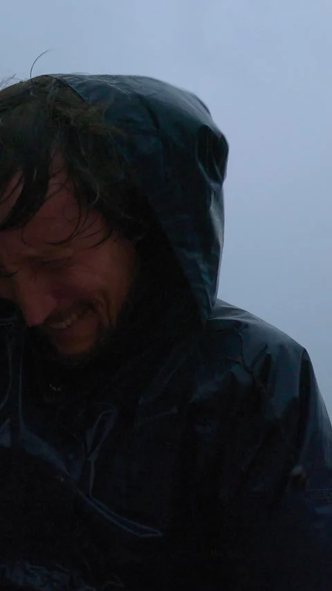 Middle aged man in a blue jacket walks through heavy rain and strong wind Stock Footage 345160746