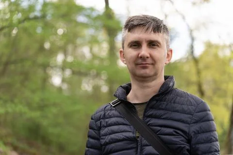 A middle-aged man on a blurred background of early spring greenery looking at Stock Photos