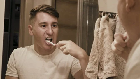A middle-aged man brushes his teeth in the bathroom Stock Footage 250397228