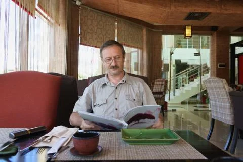 A middle-aged man in a cafe at a table waiting for chooses dishes from the me Foto stock