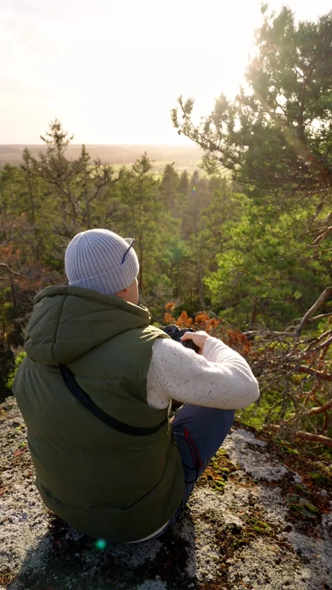 A middle-aged man with a camera on a cliff in Finnish forest Stock Footage 303783226