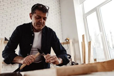 Middle-aged man carpenter working in a workshop with chisel and hammer Stock Photos