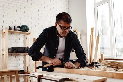 Middle-aged man carpenter working in a workshop with chisel and hammer Stock Photos
