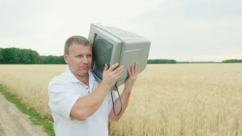 Middle-aged man carries an old TV on his shoulder. It is hard to bear and pity Stock Footage 77297910