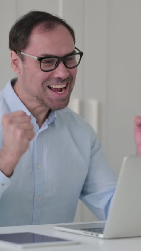 Middle Aged Man Celebrating while using Laptop in Office on Bench, Vertical 스톡 동영상 339584578