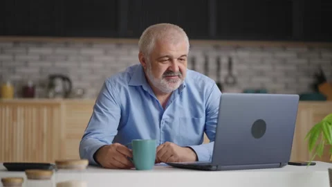 Middle-aged man is chatting by video call by laptop, sitting alone at home Stock Footage 153397952