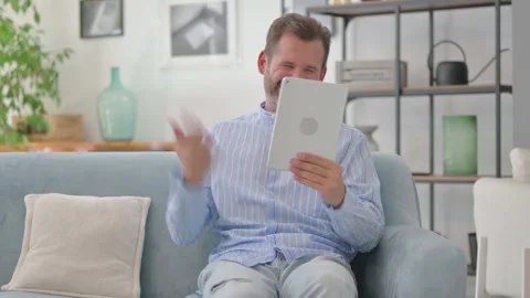 Middle Aged Man Cheering Win on Tablet while Sitting on Sofa at Home Stock Footage 287898466