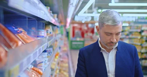 Middle-aged man choosing pack of smoked salmon in supermarket, portrait, 4K Stock Footage 232970021