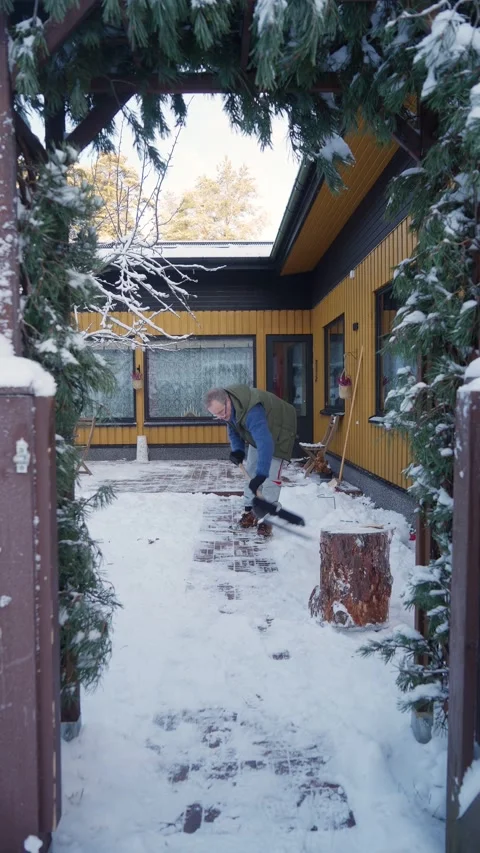 A middle-aged man is cleaning snow in the backyard Video stock 297867570